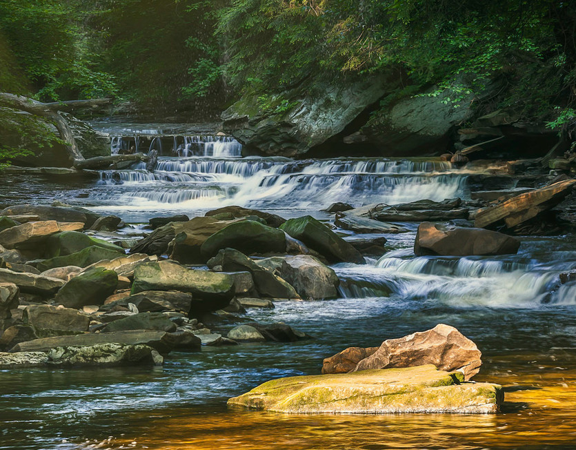 A serene waterfall cascading over rocky steps surrounded by lush green vegetation.